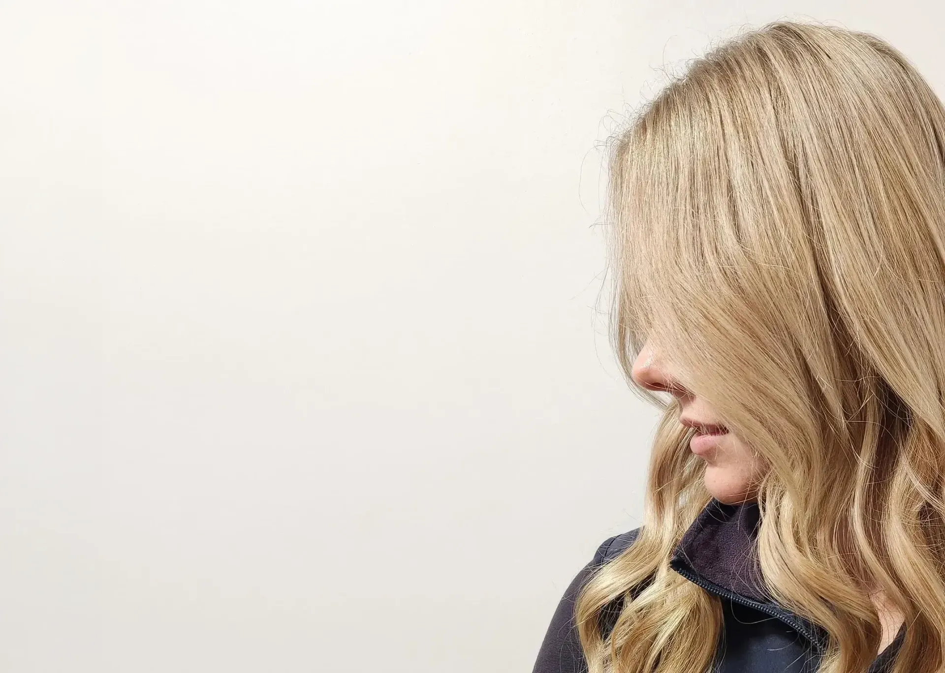 Blonde woman with long, softly waved hair styled at Honeycombe Hair Studio
